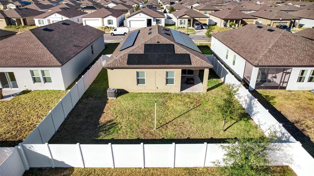 An aerial view shows the backyard and rear exterior of a house with solar panels — 5860 BOVINE DRIVE, ST CLOUD, FL