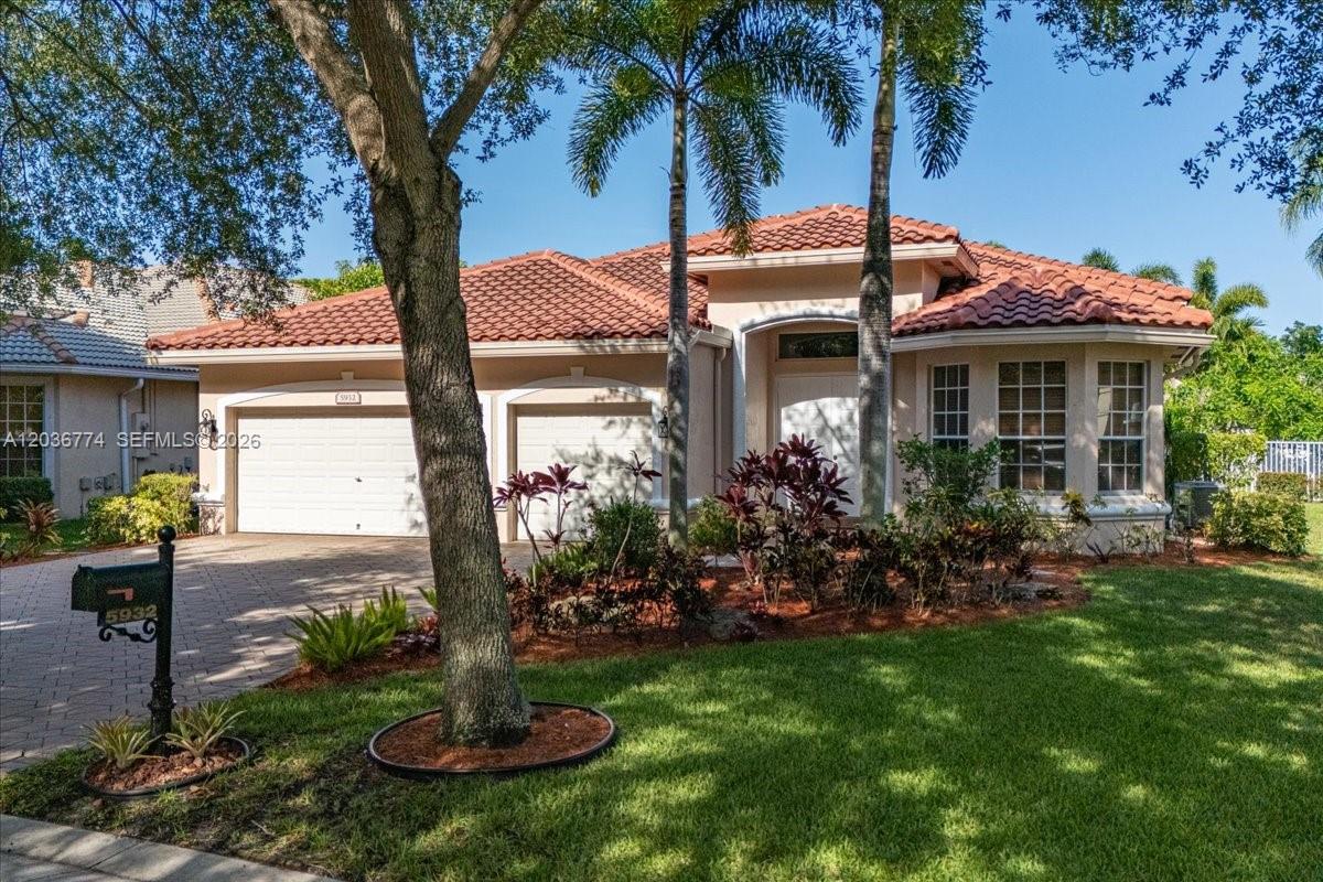 A single-story house with a tile roof, two-car garage, and landscaped front yard — CORAL SPRINGS, FL