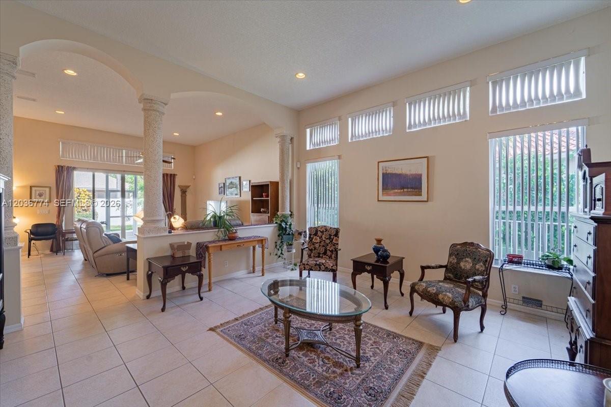 A living room features tile floors, two decorative columns, and large windows with blinds — CORAL SPRINGS, FL