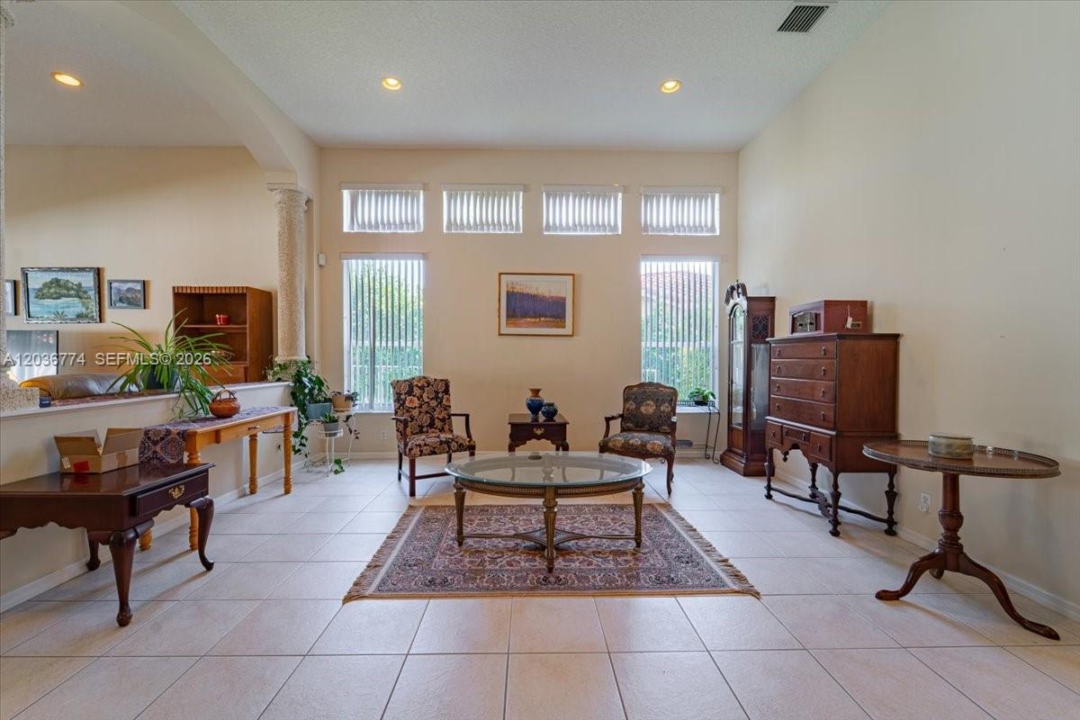 A living room with tile floors, two patterned armchairs, a glass coffee table, and windows — CORAL SPRINGS, FL