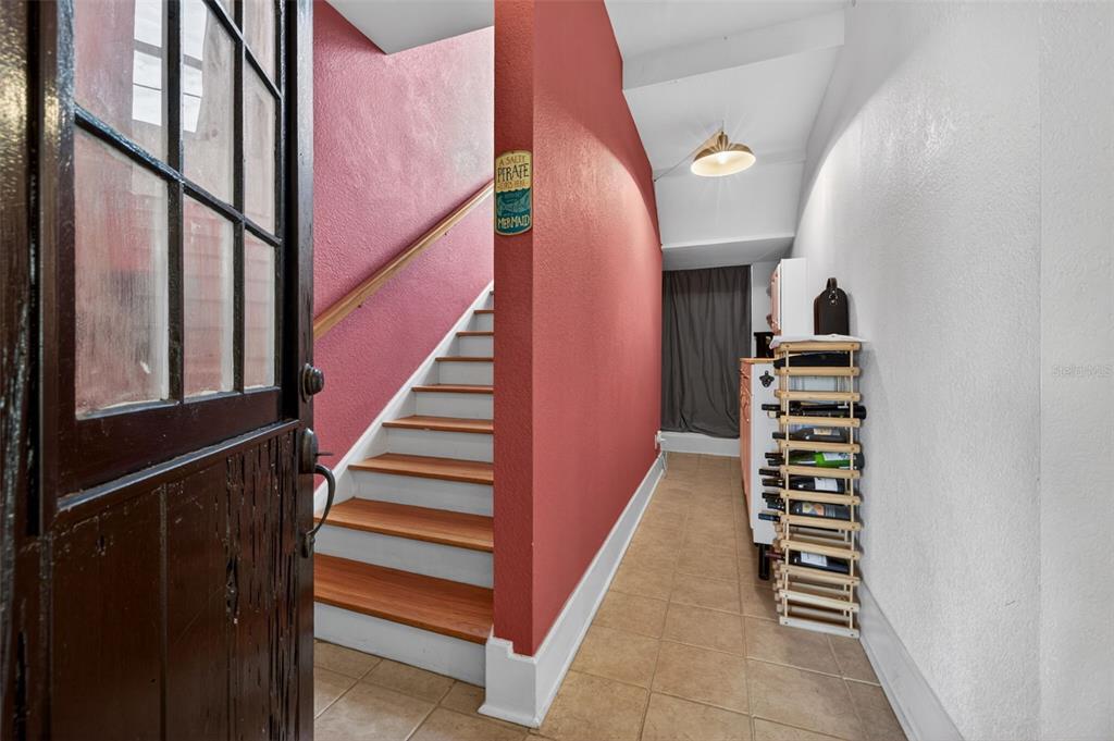 An entryway features a wooden staircase, a wine rack, and a red accent wall — 210 22ND AVENUE NE UNIT 12, ST PETERSBURG, FL