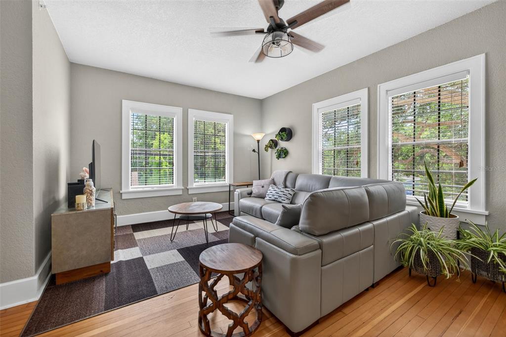 A living room features a gray leather sofa, a patterned area rug, and hardwood floors — 210 22ND AVENUE NE UNIT 12, ST PETERSBURG, FL