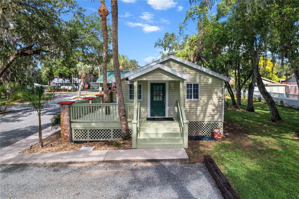 A light green cottage features a front deck, stairs, and a dark green door — 107 NE 4TH STREET, CRYSTAL RIVER, FL
