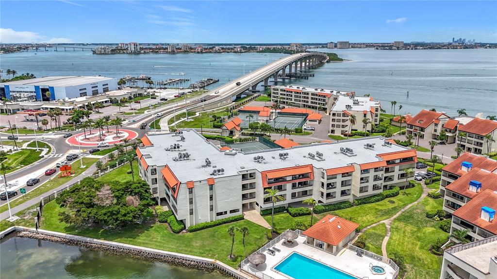 An aerial view shows a multi-story apartment complex with a swimming pool and tennis courts — 106 1ST STREET E UNIT 306, ST PETERSBURG, FL