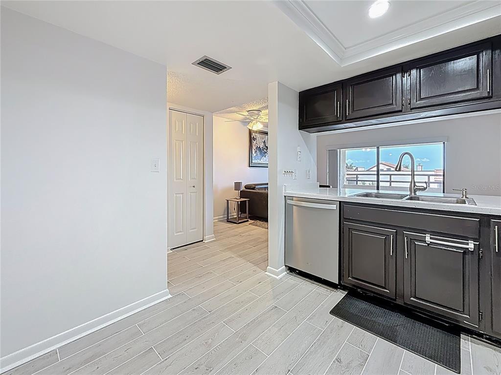 A kitchen with dark cabinets and stainless steel appliances opens into a living area — 106 1ST STREET E UNIT 306, ST PETERSBURG, FL