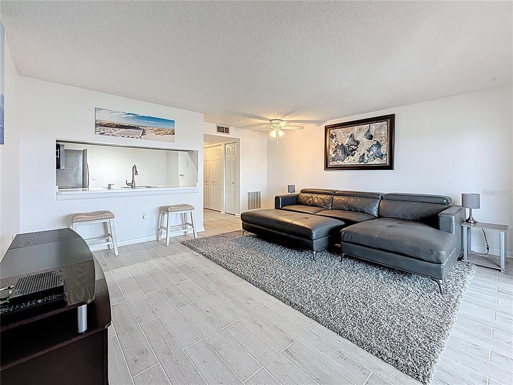 A living room features light tile flooring, a gray sectional sofa, and a kitchen pass-through — 106 1ST STREET E UNIT 306, ST PETERSBURG, FL