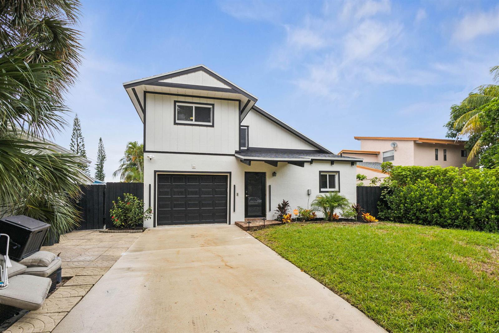 A two-story white house with a black garage door, driveway, and front lawn — 2541 Southridge Road, Delray Beach FL 33444, DELRAY BEACH, FL