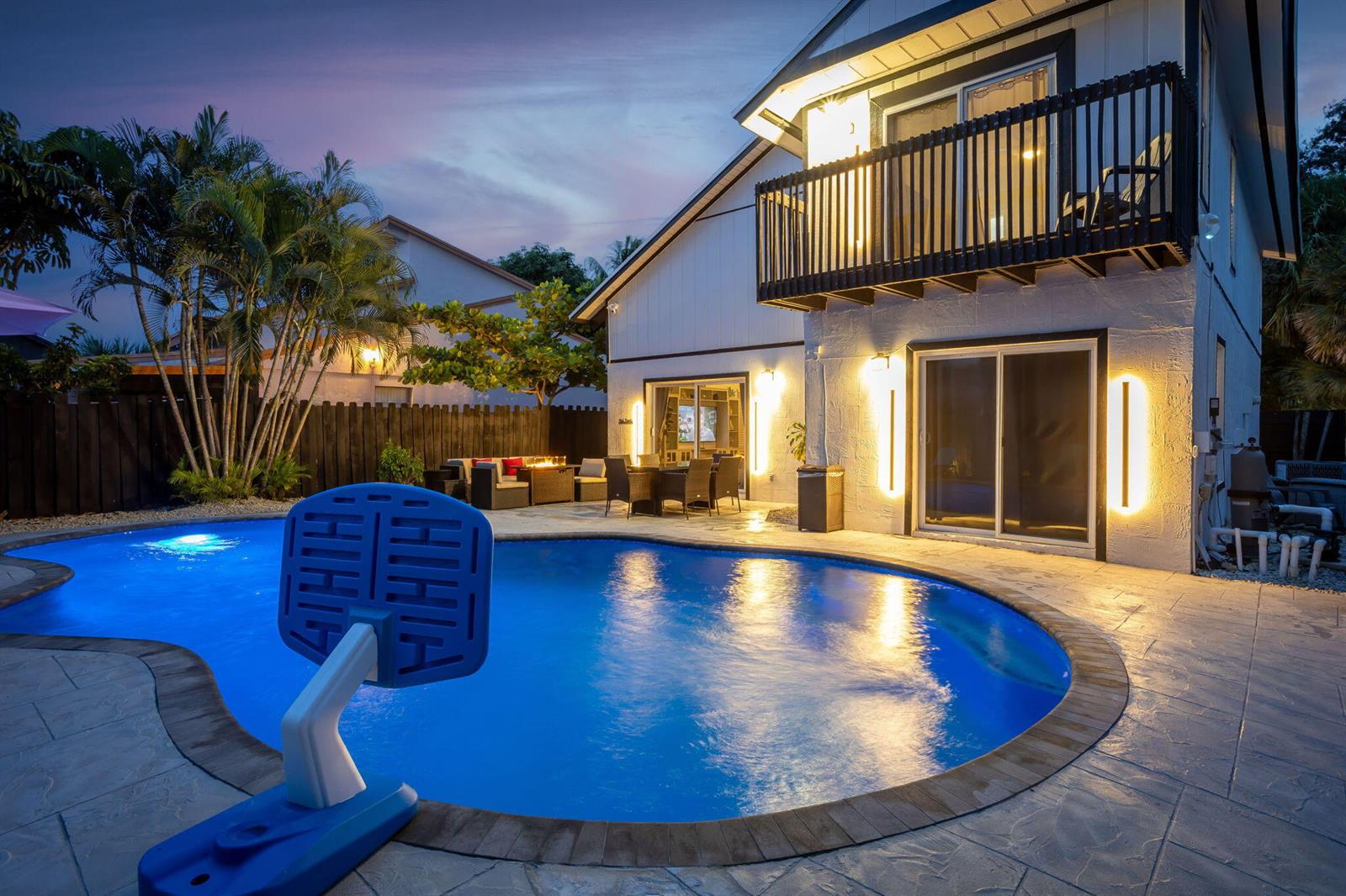 A two-story house with a balcony overlooks a backyard swimming pool at dusk — 2541 Southridge Road, Delray Beach FL 33444, DELRAY BEACH, FL