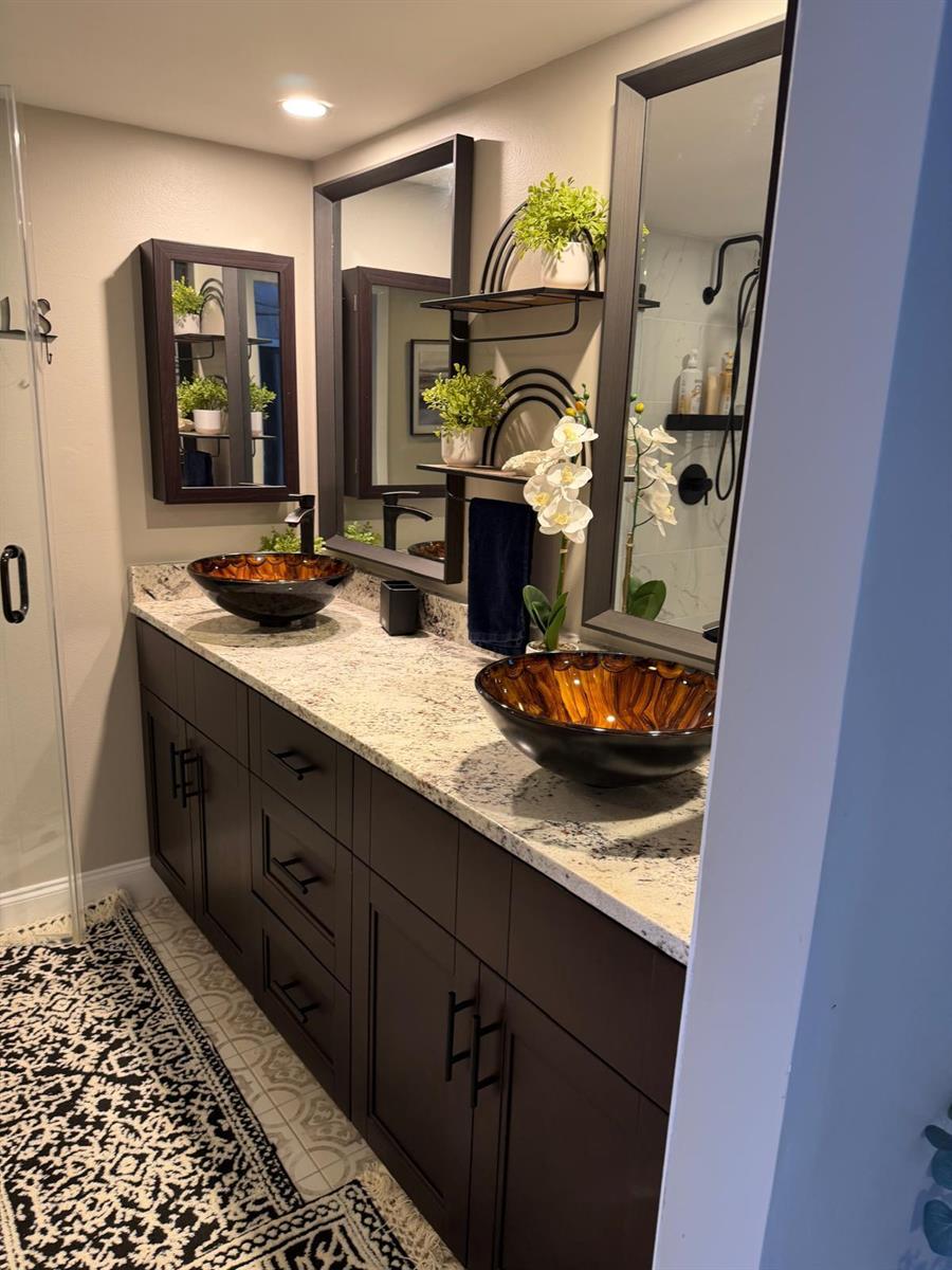 A bathroom vanity features two amber glass vessel sinks, dark cabinetry, and granite countertops — 2949 SW 22nd Circle # 27a, Delray Beach FL 33445, DELRAY BEACH, FL