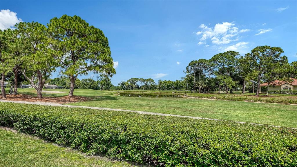 A view of a grassy golf course with a pond, trees, and a house nearby — 3374 W CHELMSFORD COURT UNIT 9, SARASOTA, FL