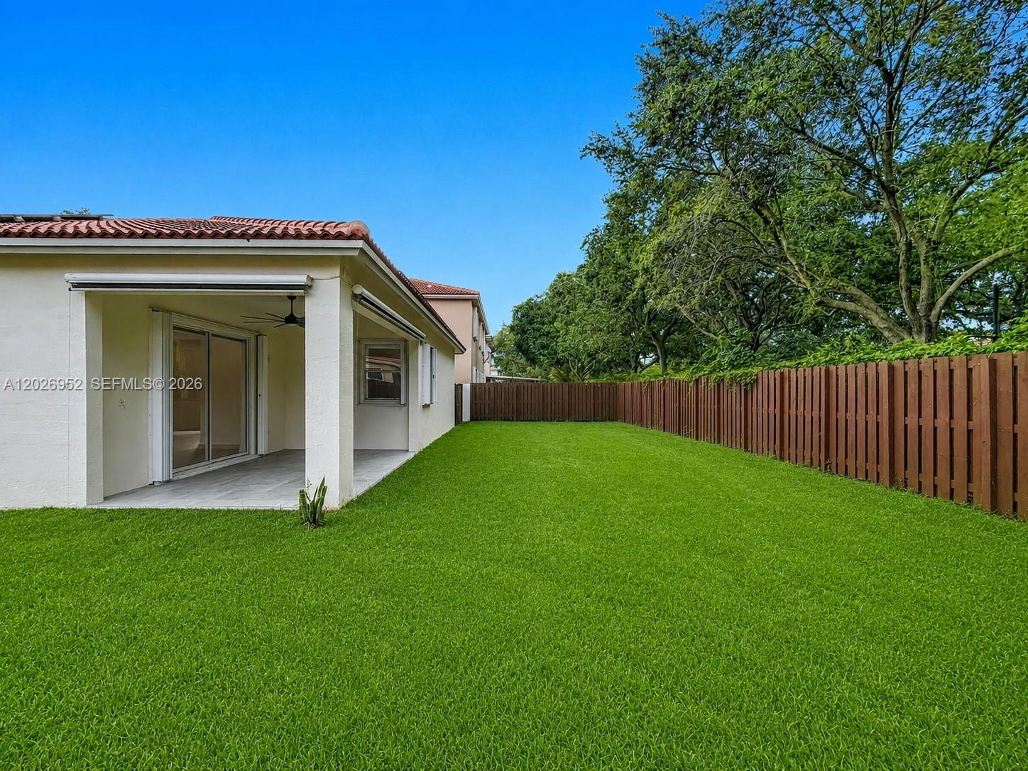 A backyard with a covered patio, green lawn, and a wooden privacy fence — 16204 Opal Creek Dr, Weston FL 33331, WESTON, FL