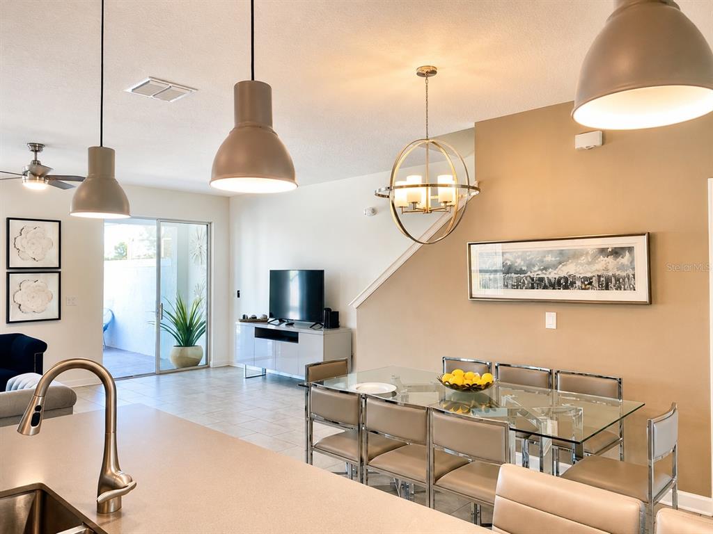 A kitchen island overlooks a dining area and living room with a glass table — 8955 CABOT CLIFFS DRIVE, DAVENPORT, FL