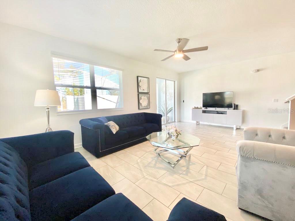 A living room features blue and light gray sofas, a glass coffee table, and tile flooring — 8955 CABOT CLIFFS DRIVE, DAVENPORT, FL