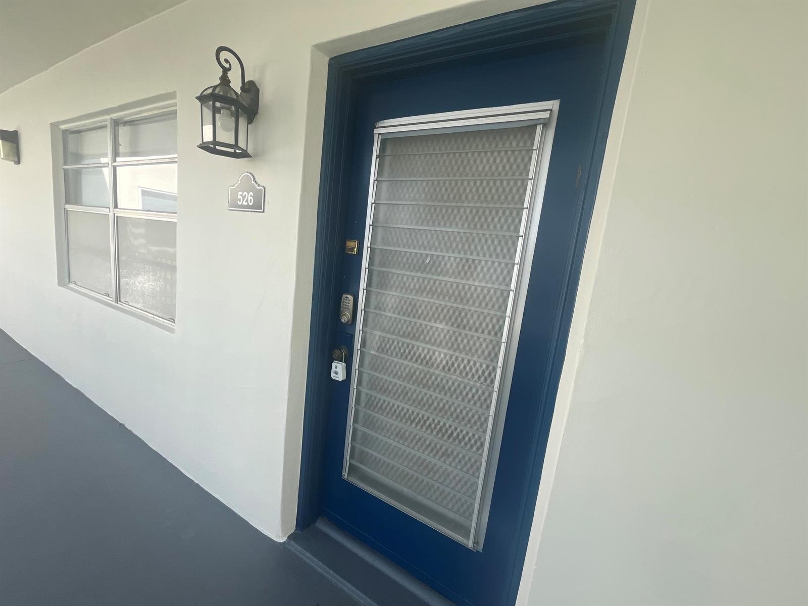 A blue front door with a security screen and a number plate sits on a walkway — 526 Normandy K, Delray Beach FL 33484, DELRAY BEACH, FL