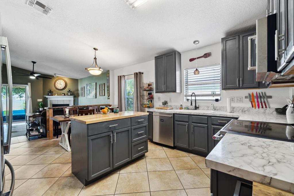 A kitchen with dark gray cabinets, a wooden island, and marble-look countertops — 24 RIVIERA ESTATES COURT, PALM COAST, FL
