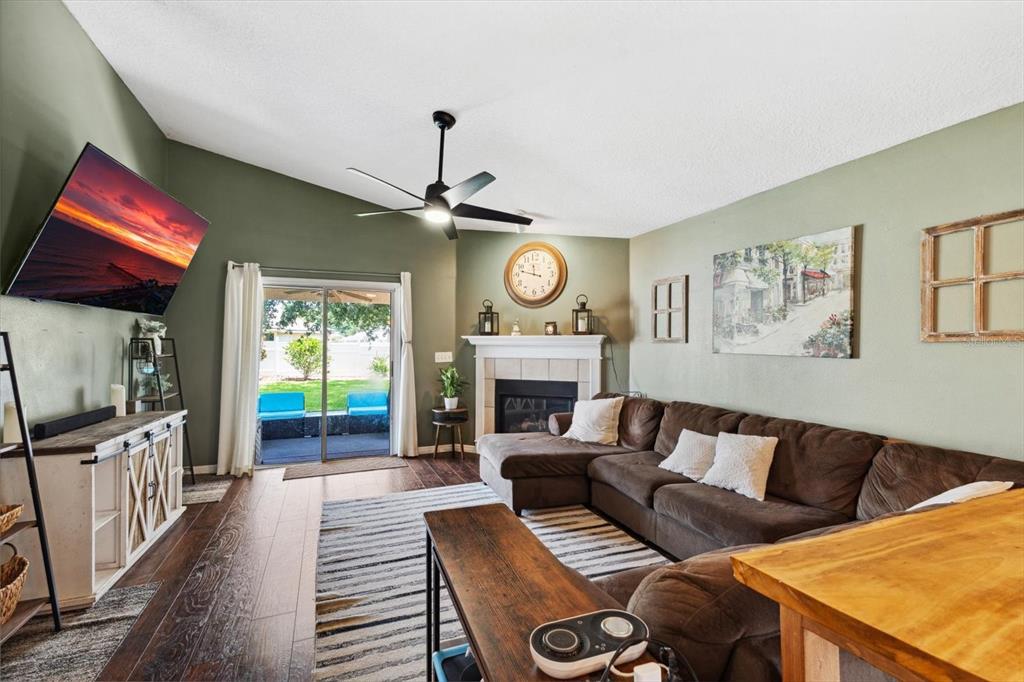 A living room features a brown sectional sofa, fireplace, ceiling fan, and sliding glass doors — 24 RIVIERA ESTATES COURT, PALM COAST, FL