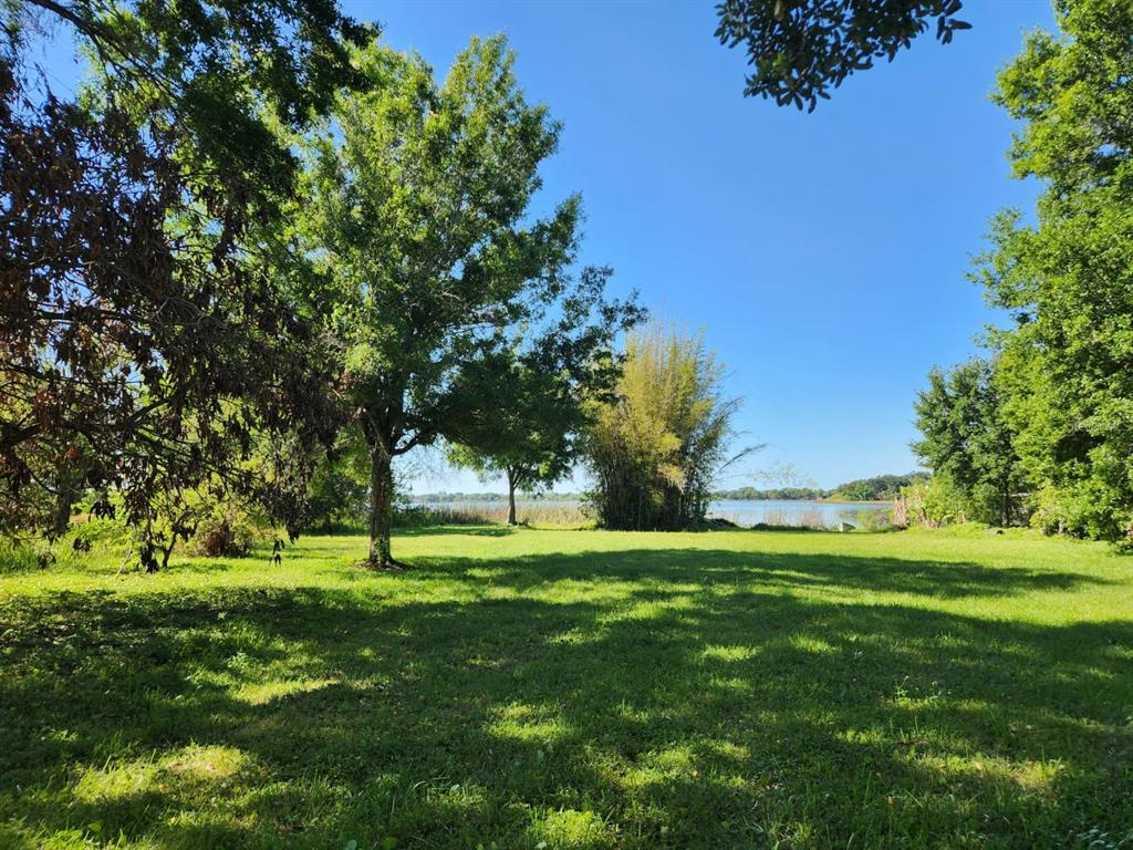 A grassy yard with mature trees leads to a view of a lake under a sky — 3898 & 3910 W WASHINGTON STREET, ORLANDO, FL