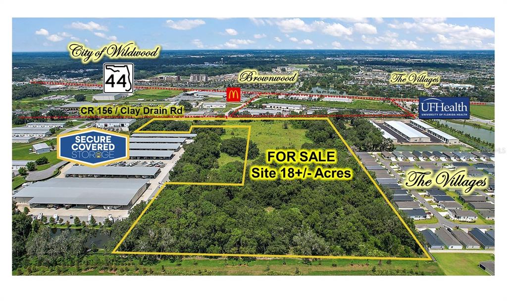 An aerial view shows a wooded 18-acre plot of land for sale near commercial developments — 4609 COUNTY ROAD 156, WILDWOOD, FL