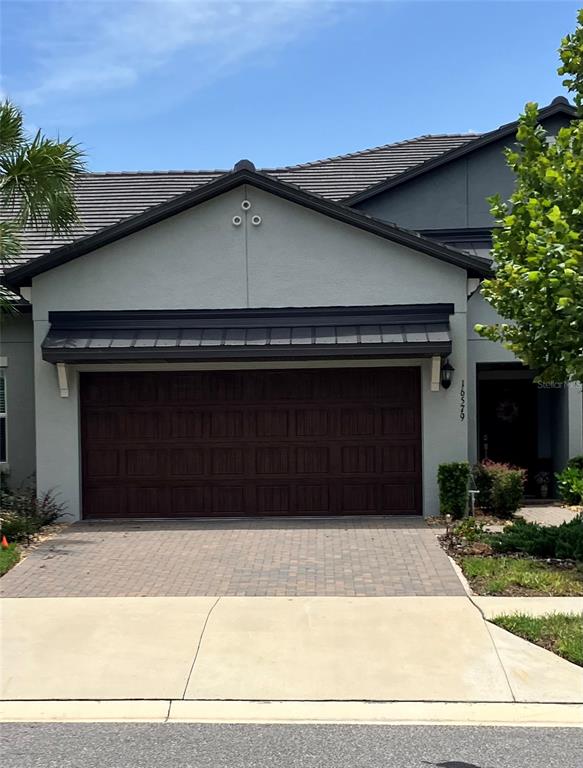 The exterior of a house features a dark brown garage door and a paved driveway — 16579 SHELL BAY DRIVE, LAND O LAKES, FL
