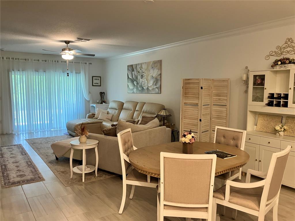 A living and dining area features tile floors, a sectional sofa, and a round wooden table — 16579 SHELL BAY DRIVE, LAND O LAKES, FL