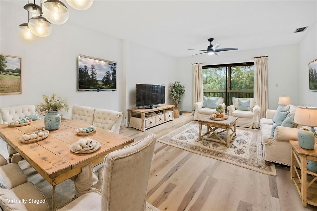 A living and dining room with light wood floors, neutral furniture, and a ceiling fan — 3800 SAXON DRIVE UNIT C52, NEW SMYRNA BEACH, FL