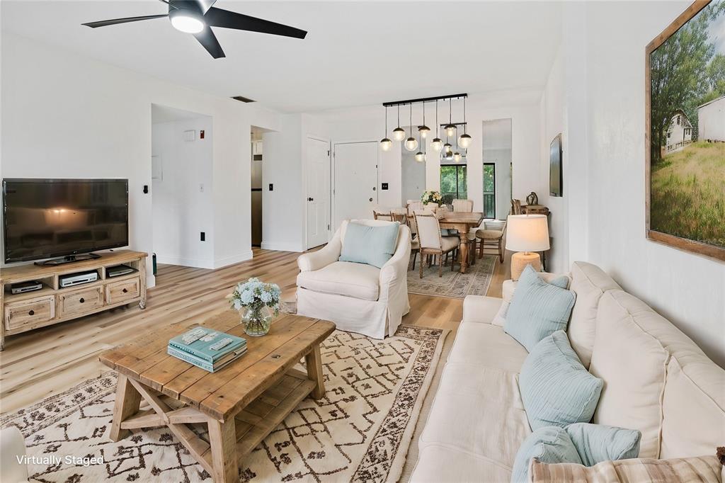 This living and dining area features light wood flooring, white walls, and neutral furniture — 3800 SAXON DRIVE UNIT C52, NEW SMYRNA BEACH, FL