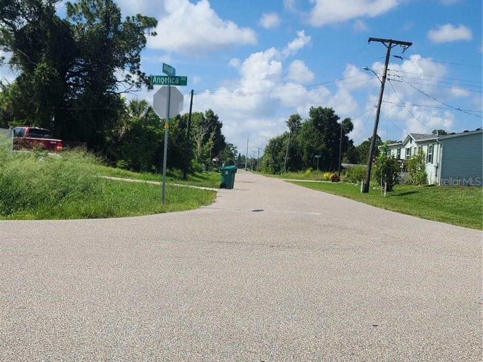 A paved residential street features a street sign for Angelica Road and a stop sign — 26532 ANGELICA ROAD, PUNTA GORDA, FL