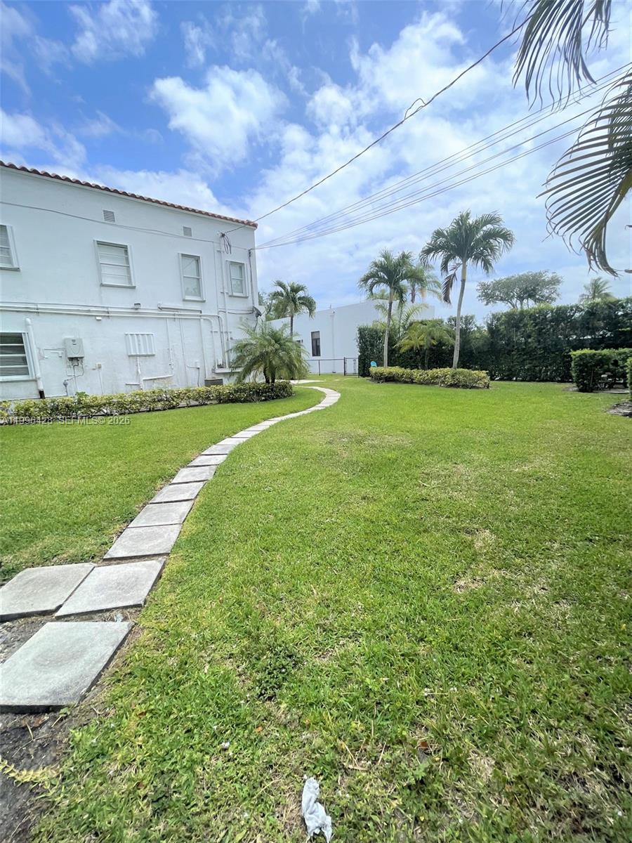 A stone walkway curves through a grassy backyard next to a white two-story building — 5116 SW 57th Ave # A, Miami FL 33155, MIAMI, FL