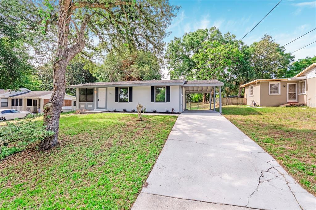 A single-story house with a concrete driveway and carport sits on a grassy lawn — 133 COLOMBA ROAD, DEBARY, FL
