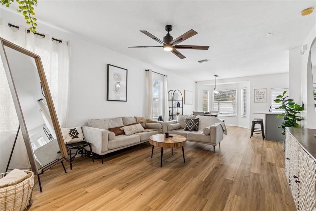 A living room features light wood flooring, two sofas, a coffee table, and a ceiling fan — 12610 ADVENTURE DRIVE, RIVERVIEW, FL