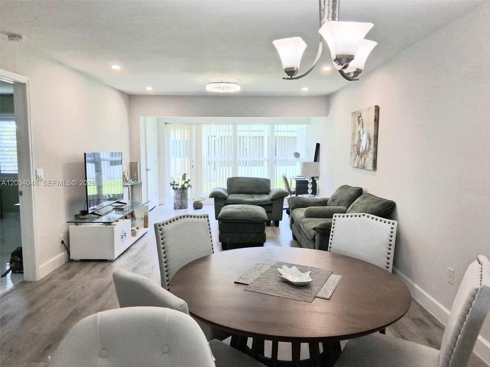A dining area with a round table opens into a living room with green furniture — 1150 Boxwood Dr # 101, Delray Beach FL 33445, DELRAY BEACH, FL