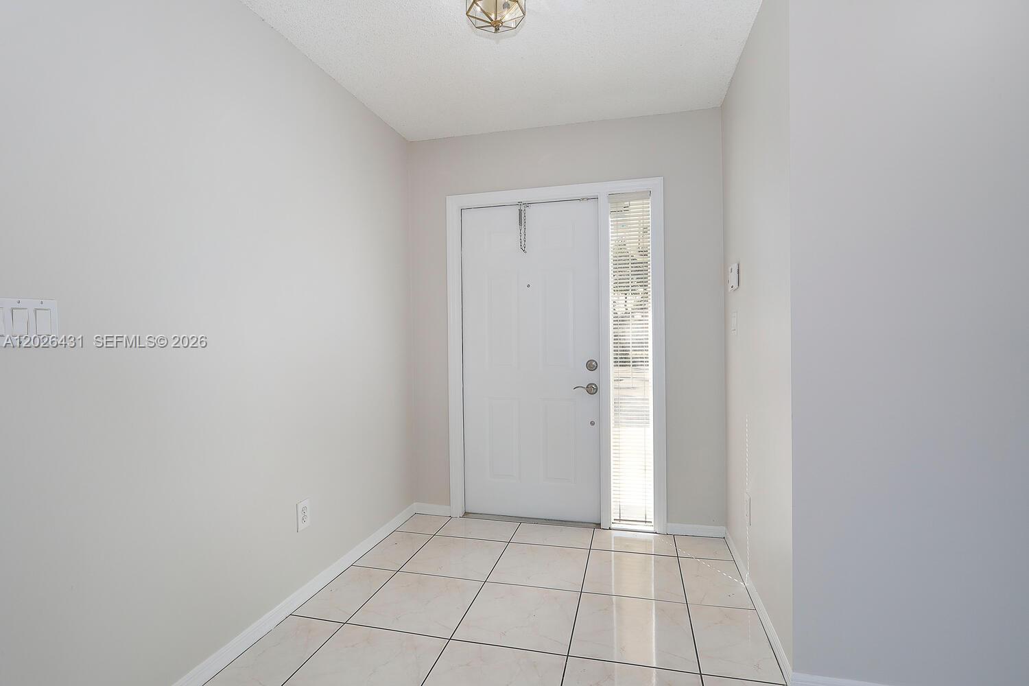 An entryway features light-colored tile flooring, white walls, and a white front door with sidelights — 12357 SW 144th Ter, Miami FL 33186, MIAMI, FL