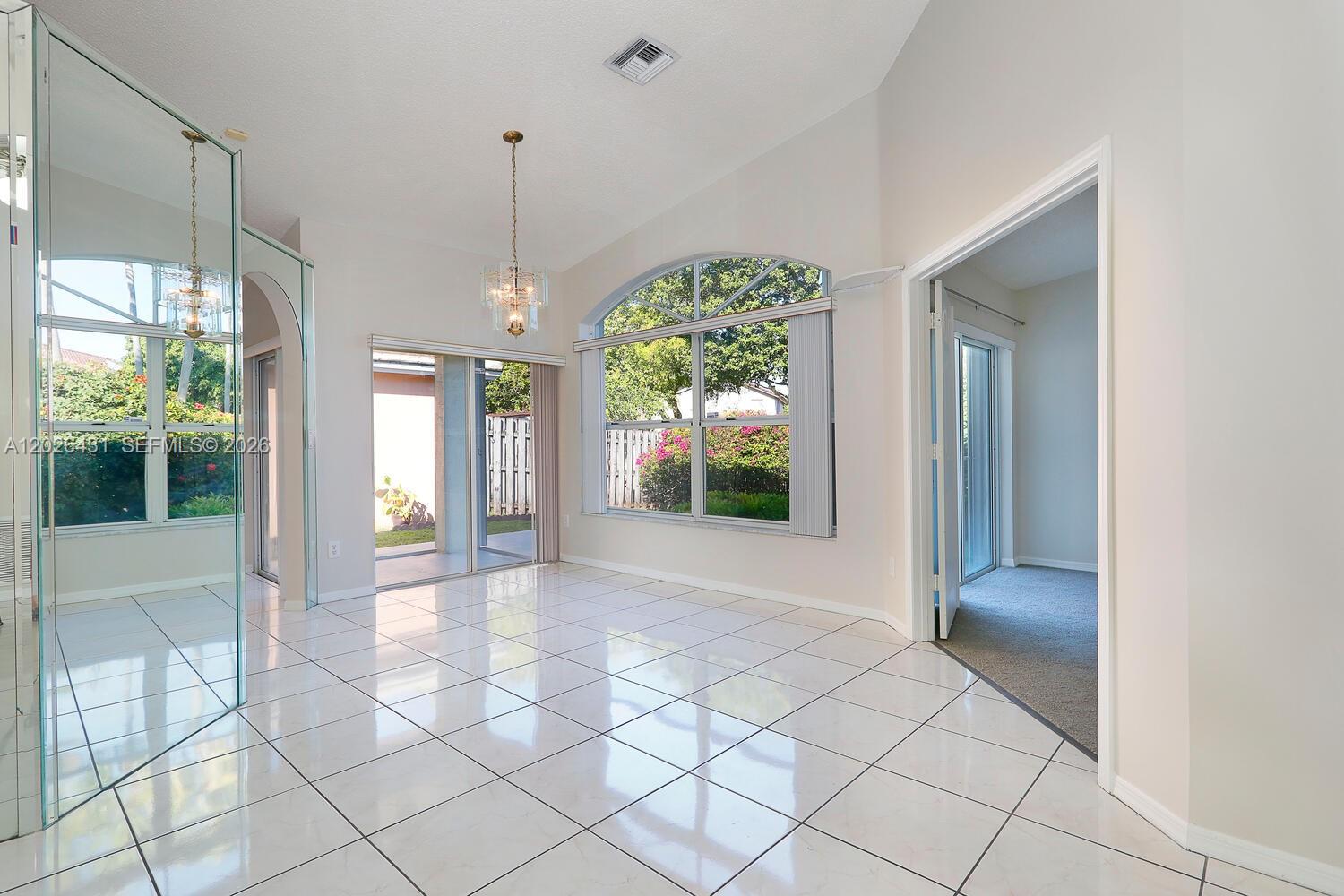 A bright dining room features white tile floors, a vaulted ceiling, and large arched windows — 12357 SW 144th Ter, Miami FL 33186, MIAMI, FL