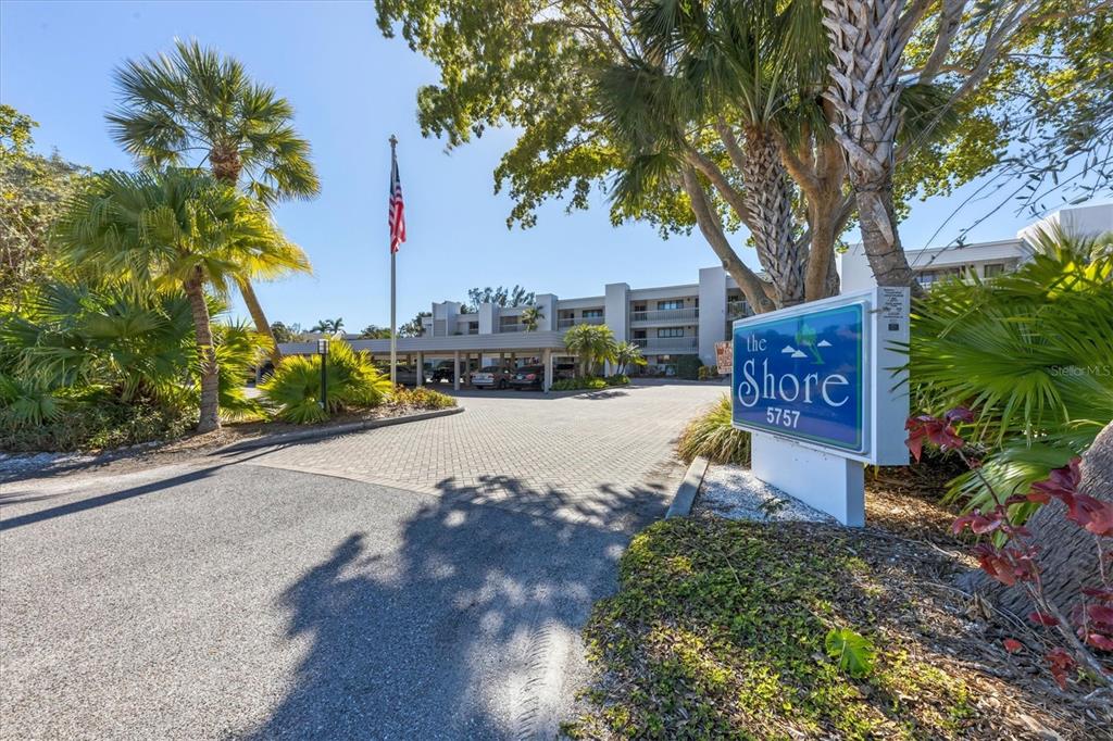 An exterior view of a multi-story apartment building with a sign and palm trees — 5757 GULF OF MEXICO DRIVE UNIT 305, LONGBOAT KEY, FL