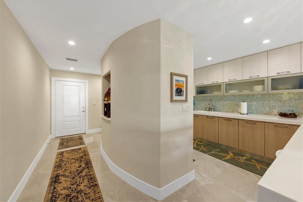 A hallway leads to a kitchen area with light wood cabinets and a decorative backsplash — 5757 GULF OF MEXICO DRIVE UNIT 305, LONGBOAT KEY, FL