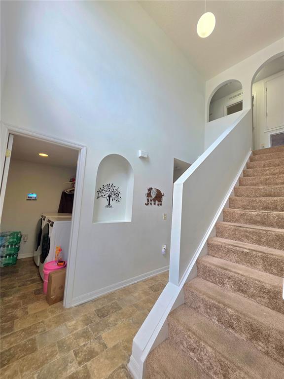 A high-ceilinged entryway features carpeted stairs, a tiled floor, and a laundry room alcove — 9055 PEMBERTON STREET, SPRING HILL, FL