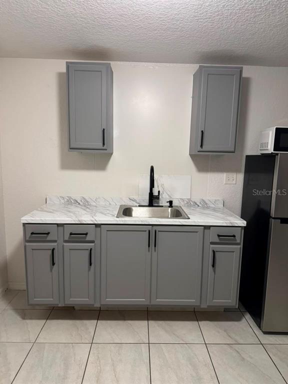 A kitchen with white walls, tiled floors, a ceiling fan, and a black refrigerator — 109 N OAKLAND STREET, LEESBURG, FL