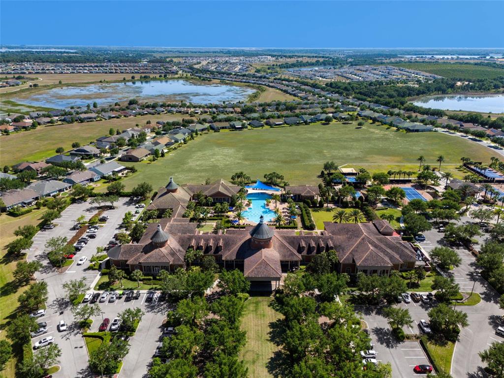 An aerial view shows a large community clubhouse with a pool, parking, and surrounding homes — 115 CRESCENT MOON DRIVE, GROVELAND, FL