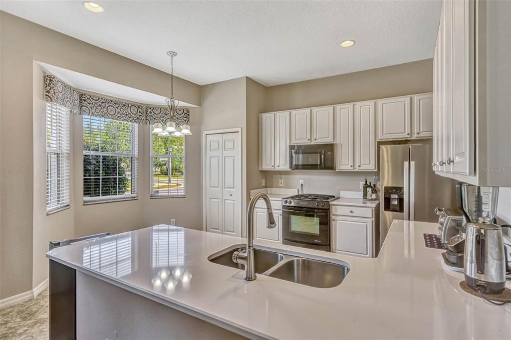 A kitchen features white cabinets, a quartz island with a sink, and a breakfast nook — 115 CRESCENT MOON DRIVE, GROVELAND, FL