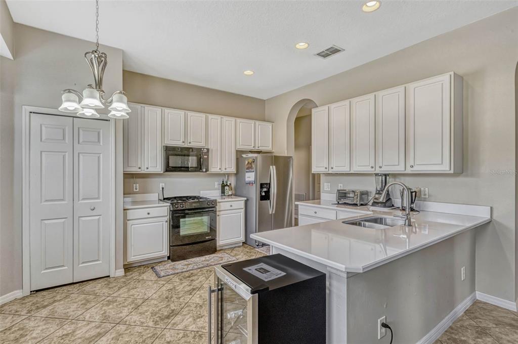 A kitchen features white cabinets, stainless steel appliances, a breakfast bar, and tile flooring — 115 CRESCENT MOON DRIVE, GROVELAND, FL