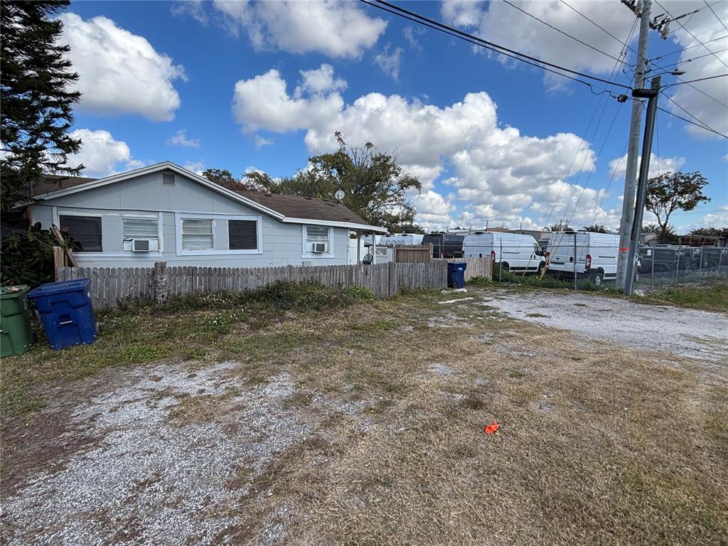 A light blue house with a wooden fence sits behind a gravel and grass lot — 4213 W CAYUGA STREET, TAMPA, FL
