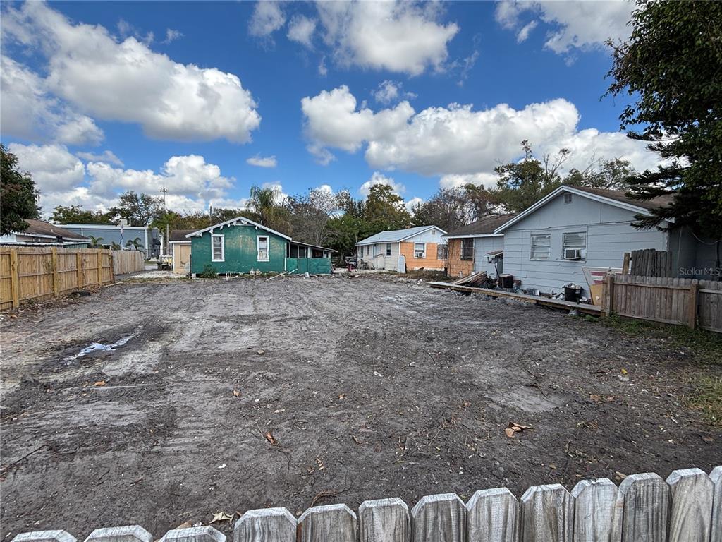 A vacant dirt lot is situated between several small residential houses under a cloudy sky — 4213 W CAYUGA STREET, TAMPA, FL