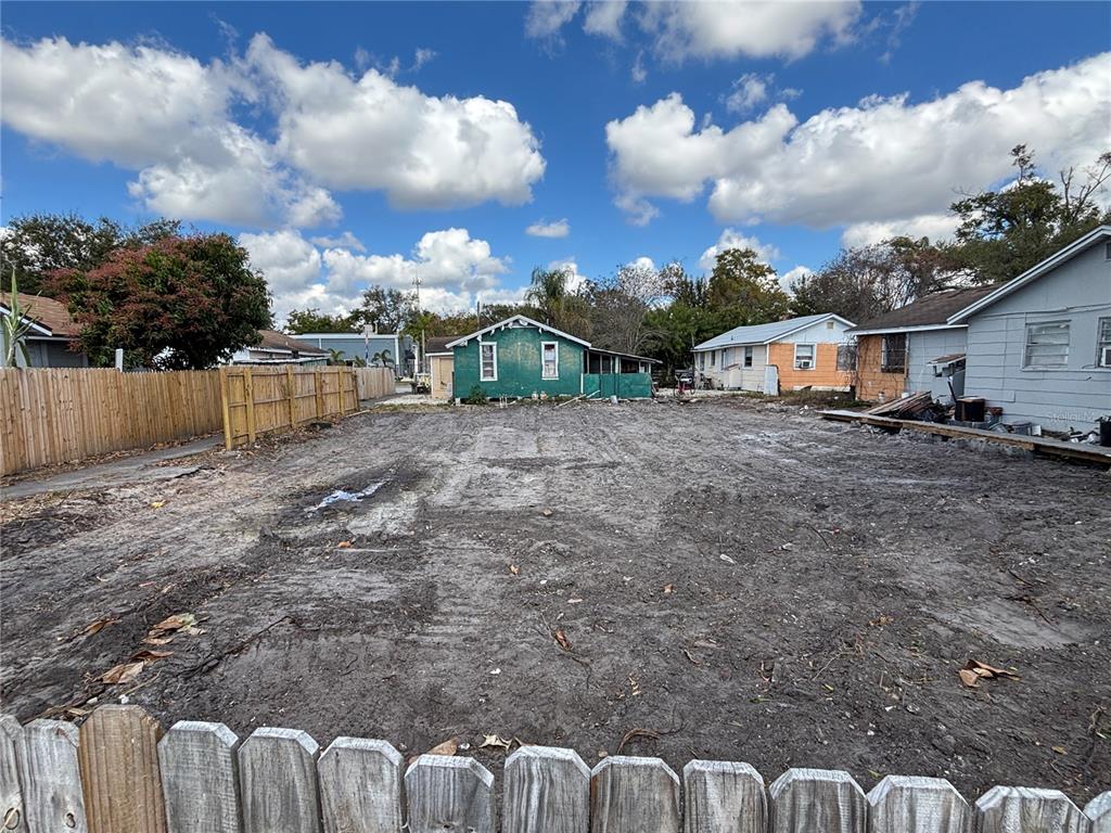 A vacant, dirt-covered residential lot sits between a green house and a light-colored house — 4213 W CAYUGA STREET, TAMPA, FL