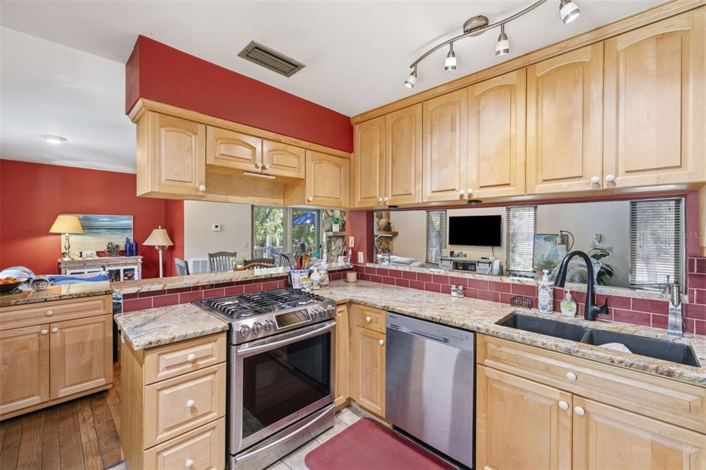 A kitchen features light wood cabinets, granite countertops, stainless steel appliances, and a red backsplash — 13150 72ND TERRACE, SEMINOLE, FL