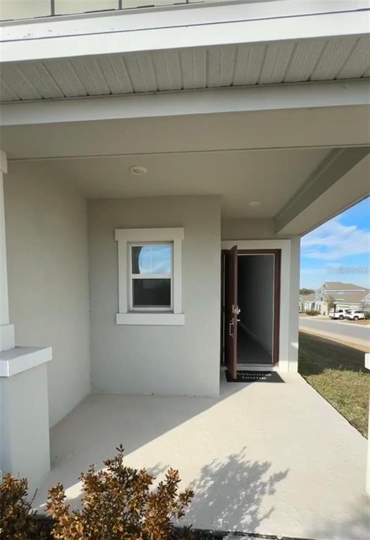 A covered front porch features a single window, a brown door, and a concrete floor — 2002 PUNCH BOWL AVENUE, DAVENPORT, FL