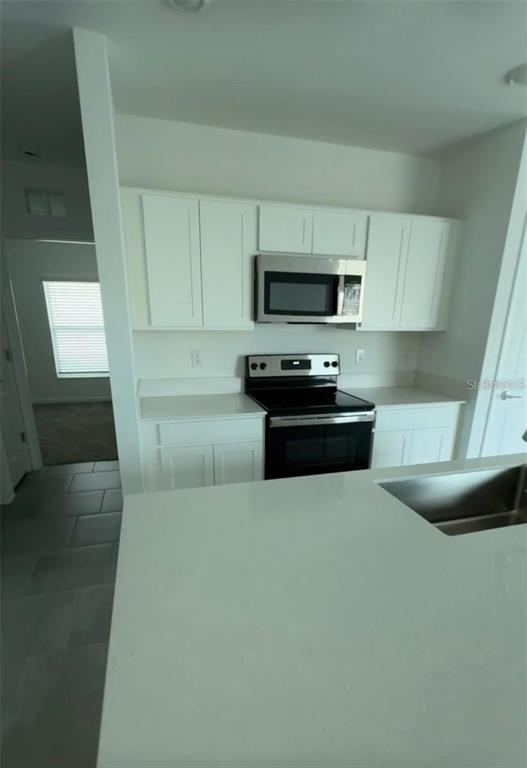 A kitchen features white cabinets, stainless steel appliances, and a white countertop island — 2002 PUNCH BOWL AVENUE, DAVENPORT, FL
