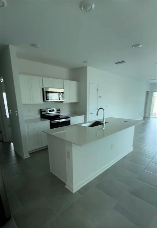 A modern kitchen features white cabinets, stainless steel appliances, and a large central island — 2002 PUNCH BOWL AVENUE, DAVENPORT, FL