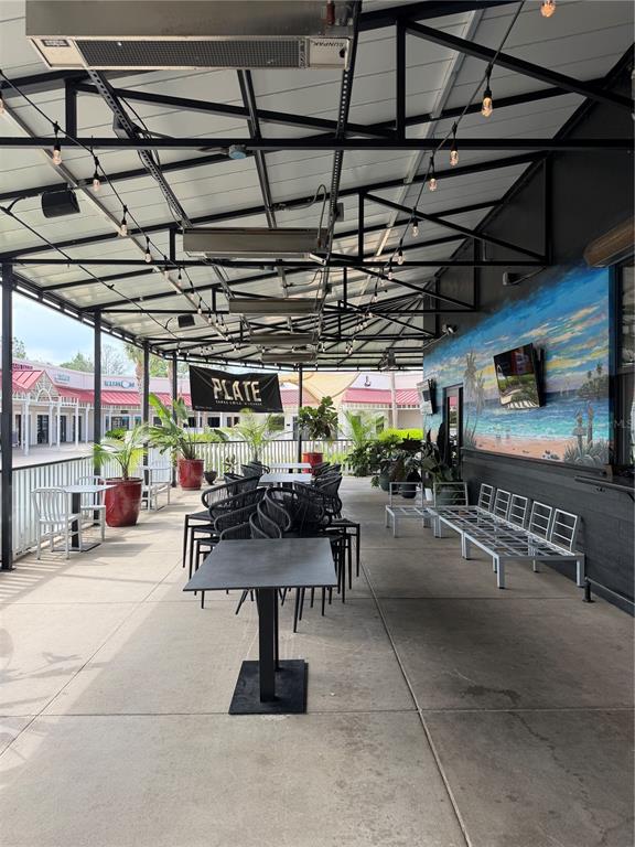 An outdoor covered patio features metal tables, chairs, and a large beach mural on the wall — 13134 DALE MABRY HIGHWAY, TAMPA, FL