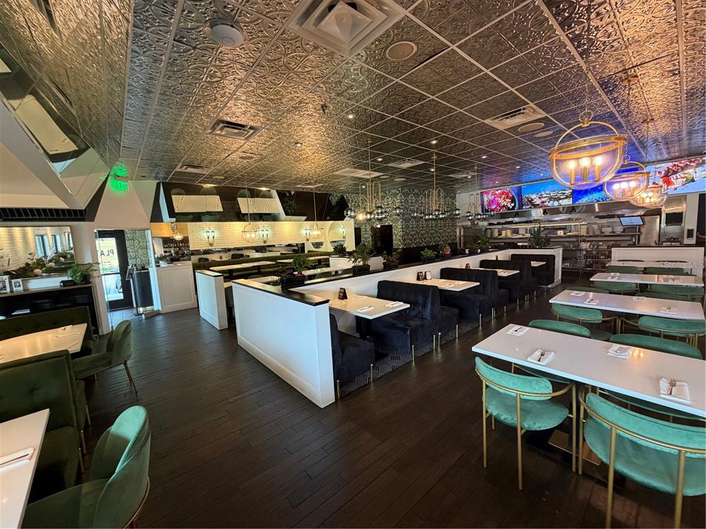 A restaurant dining room features dark wood floors, velvet booths, and a metallic patterned ceiling — 13134 DALE MABRY HIGHWAY, TAMPA, FL