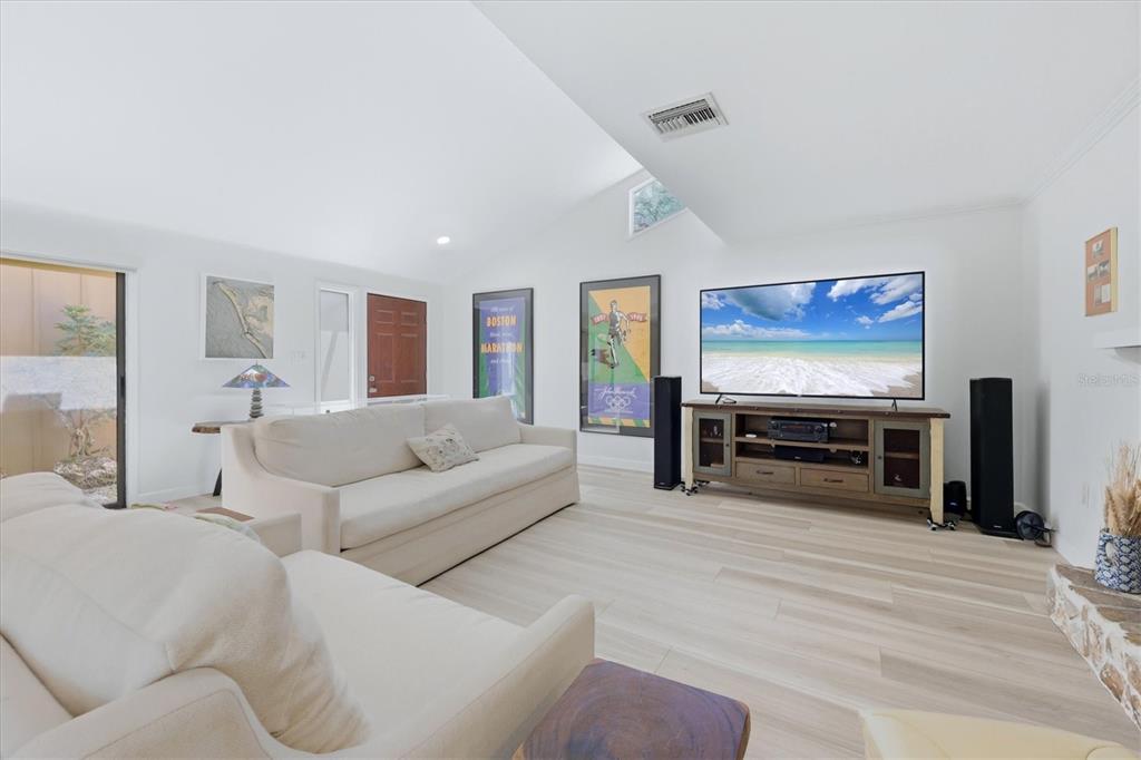 A bright living room features white walls, light wood-look flooring, two sofas, and a television — 2510 NIGHTINGALE LANE UNIT 54, BRADENTON, FL